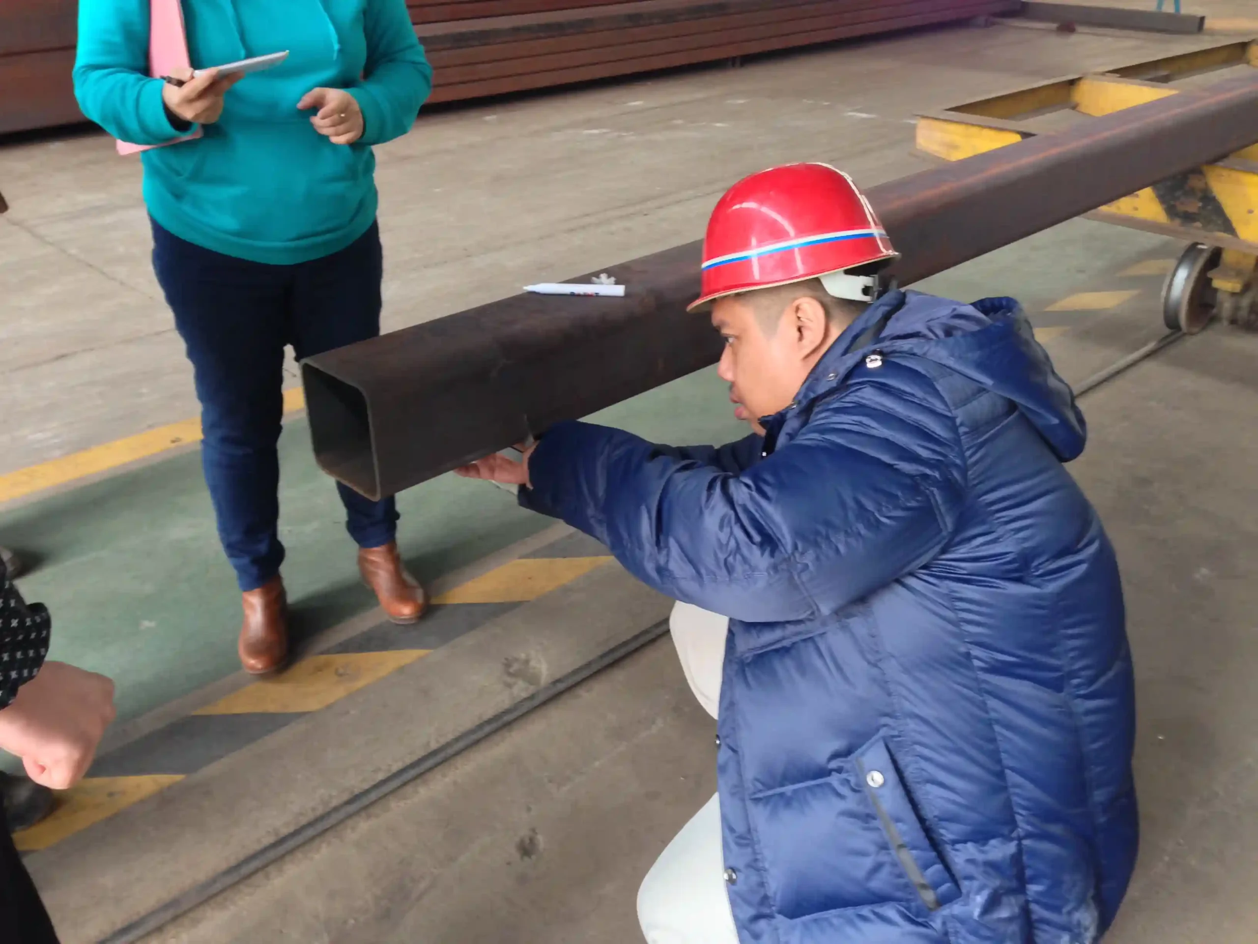 Third party inspector measuring steel members before container loading