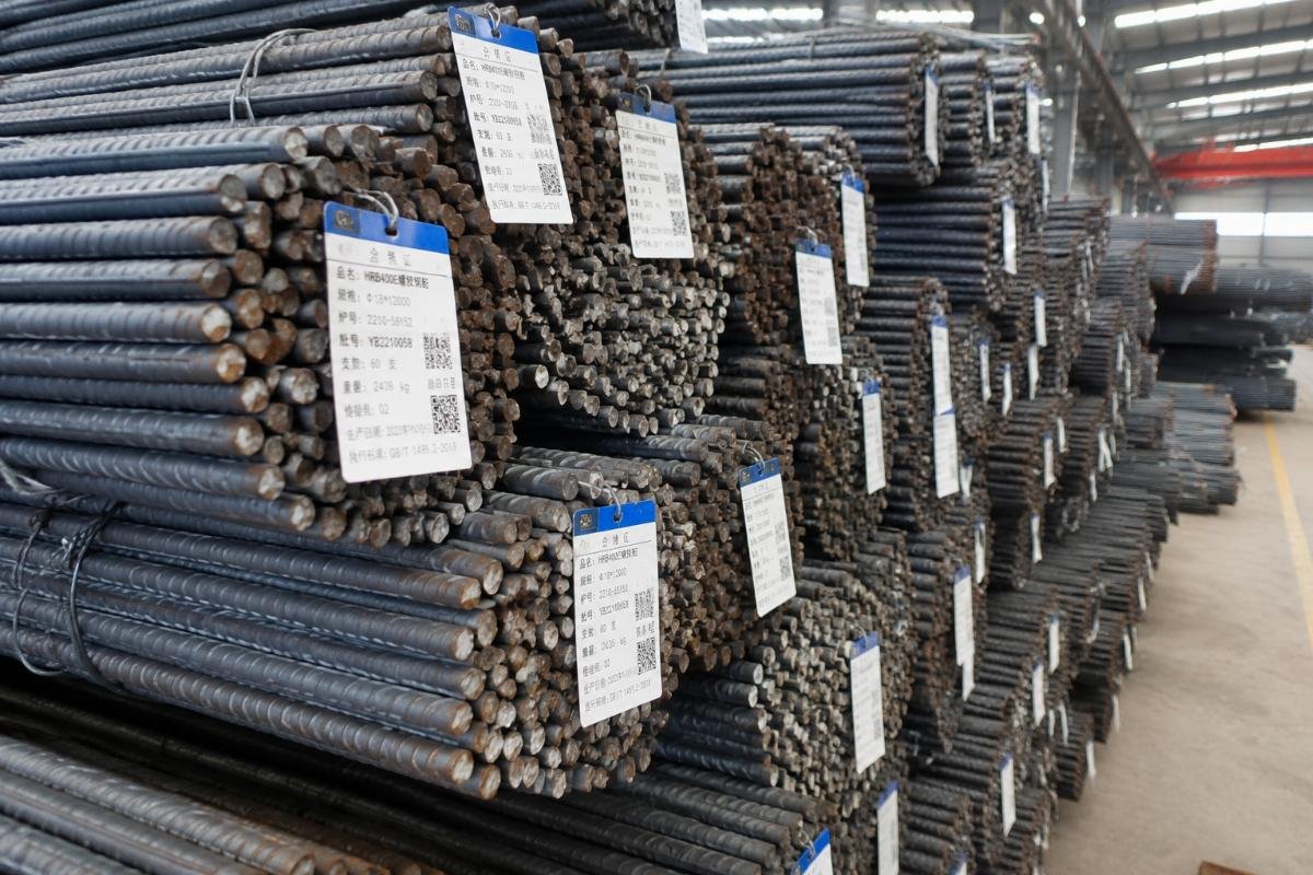 Stacked steel rebar bundles with clear identification tags at a warehouse