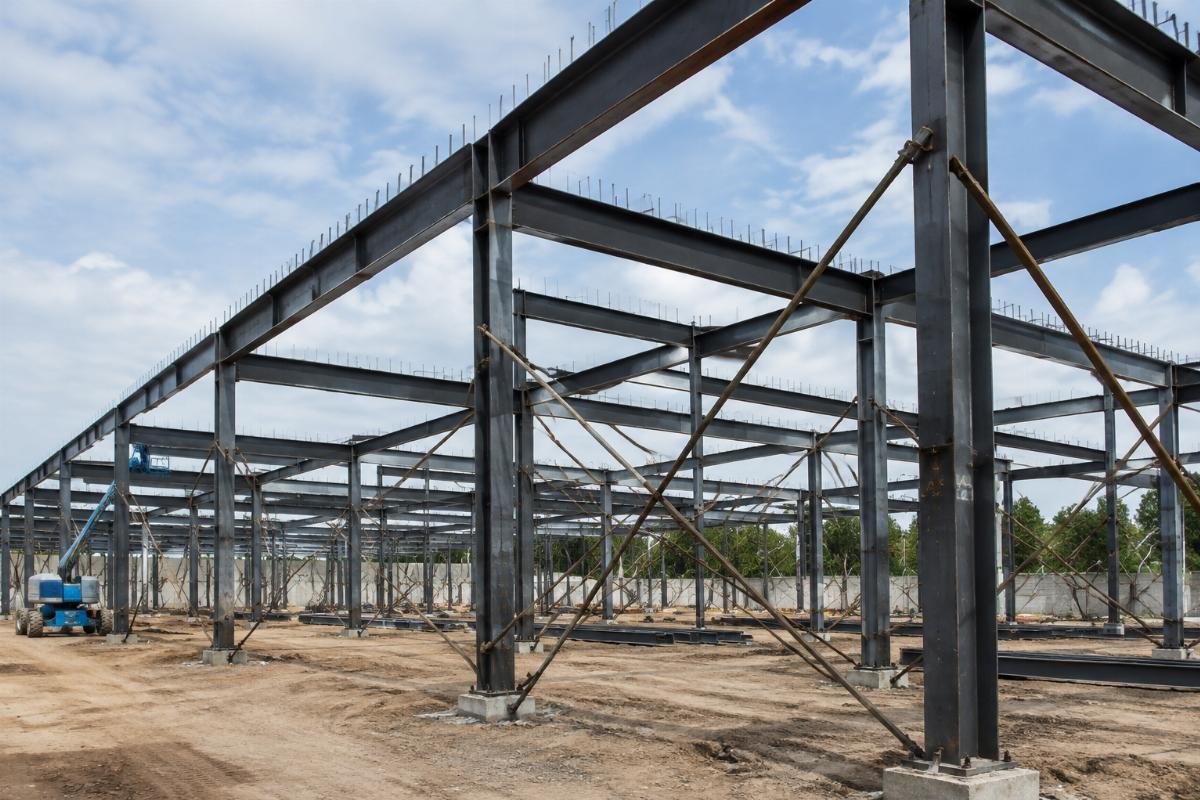 Warehouse construction site showing structural steel beams installed with temporary bracing